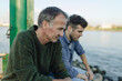 © Gustafsson/Westend61 - Son and father looking down while sitting by river