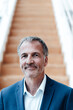 © Gustafsson/Westend61 - Smiling male business professional standing against staircase in corridor at office