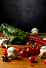 Ruby Red Chard With Edible Mushrooms And Cherry Tomatoes On Wooden Table