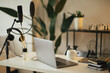 © polinaloves - Items for recording podcast: professional microphone, earphones and laptop on white table in studio with white walls.