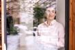 © Katharina Mikhrin/Westend61 - Smiling female entrepreneur with coffee mug looking away seen through glass window
