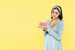 © LIGHTFIELD STUDIOS - doubting, pregnant woman holding piece of delicious cake isolated on yellow.