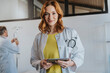 © Mareen Fischinger/Westend61 - Female doctor holding digital tablet while standing with coworker in background at clinic