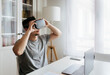 © Marco Govel/Westend61 - Male entrepreneur holding Virtual reality headset while sitting with laptop on desk at home office