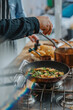 © Mareen Fischinger/Westend61 - Chef sprinkling vegetable leaf over food in frying pan while standing by colleague in kitchen