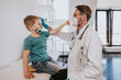 © Mareen Fischinger/Westend61 - Male pediatrician with protective face mask checking boy in medical examination room