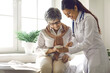 © Studio Romantic - Caring doctor teaches female patient to use mobile healthcare app. Retired lady sitting in hospital exam room looking at cell screen learning to download health tracker for senior citizens. Copy space