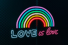 Illuminated Rainbow With Text On Chainlink Fence