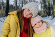 © Oxana Guryanova/Westend61 - Smiling sisters in warm clothing standing together against trees during snow