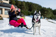 © Oscar Carrascosa Martinez/Westend61 - Woman photographing through mobile phone while sitting by Siberian Husky on snow covered field during winter