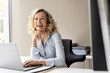 © peter scholl/Westend61 - Laughing female business professional with laptop sitting in office