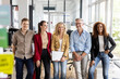 © peter scholl/Westend61 - Smiling male and business professionals leaning at desk in office