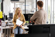 © peter scholl/Westend61 - Smiling businesswoman with laptop discussing with young colleague while leaning at desk in office