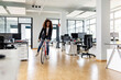 © peter scholl/Westend61 - Cheerful businesswoman riding bicycle in open plan office