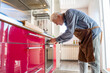 © VITTA GALLERY/Westend61 - Senior man with apron preparing food in oven at kitchen