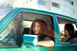 © LOUIS CHRISTIAN/Westend61 - Smiling woman looking away while sitting with friends in car