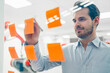 © Daniel Ingold/Westend61 - Smiling young male engineer writing on adhesive notes sticked at glass wall