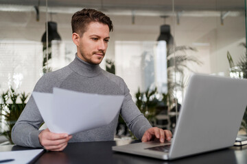 Confident businessman working on laptop at office