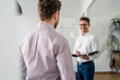 © Daniel Ingold/Westend61 - Smiling businessman with clipboard looking at male colleague in office