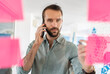 © Daniel Ingold/Westend61 - Young businessman talking on mobile phone about adhesive note at office