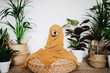 © Eva Blanco/Westend61 - Playful dog wrapped in blanket sitting on ottoman stool by houseplant at home