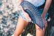 Horizontal close up image on woman legs in blue jeans shorts standing outdoors and holding a blue hand fan.