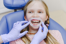 Portrait Of Little Girl Wearing Dental Gag Lying In Dentists Chair During Exam
