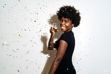 Curly Hair Woman Showing Champagne Flute While Standing Against White Background