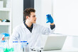 © Giorgio Fochesato/Westend61 - Male scientist looking at liquid in test tube while working on laptop in laboratory