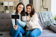 © Giorgio Fochesato/Westend61 - Smiling mother with holding mug vlogging with daughter through mobile phone while sitting on sofa at home