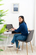 © Giorgio Fochesato/Westend61 - Young woman sitting with laptop by table at home office