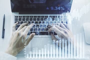 Multi exposure of abstract creative financial graph with hand typing on laptop on background, forex and investment concept