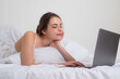 © Volodymyr - Working home concept. Pretty woman lying on bed blogging on laptop in bedroom.