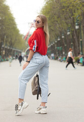 Wall Mural - Beautiful girl in a red top high waist jeans walking street.