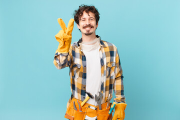 young handyman housekeeper smiling and looking friendly, showing number two