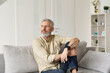 © insta_photos - Relaxed mature older thoughtful tattooed hipster man relaxing sitting on sofa and thinking at home. Pensive calm stylish mid aged single bearded guy resting on couch at home looking away, reflecting.