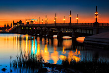 The Bridge Of Lions In St. Augustine, Florida, At Twilight With The Bridge's Lights Reflecting Colorful Patterns In The River Below.