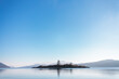 © Tandem Stock - A small island sits across from East Sound on Orcas Island with calm skies and waters.