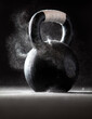 © Tandem Stock - Dramatic product image of a black CrossFit kettlebell with tape on the handle and chalk dust swirling off of it.