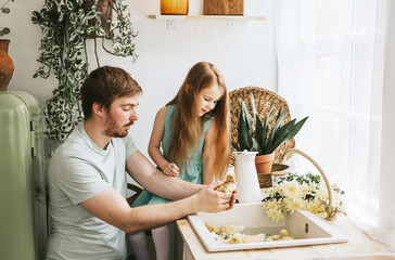 Wall Mural - dad young man and his little girl daughter stands in the kitchen of a country house with duckling in hands and bathing in sink, summer vibes concept