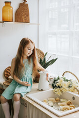 Wall Mural - little red haired girl is sitting in the kitchen of a country house with duckling bathing in sink, summer vibes concept