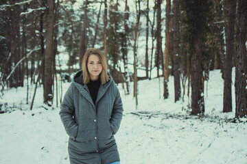 Poster - Closeup shot of a blonde female in a down jacket in a forest