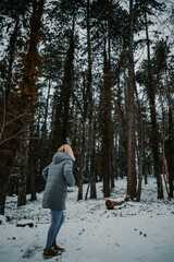 Poster - Vertical shot of a blonde female in a down jacket in a forest