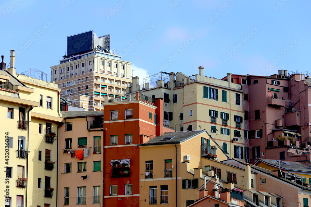 Genoa, Italy. Wide view of colorful houses in Genoa historic city center against a contemporary building and a blue sky in the San Agostino hill.