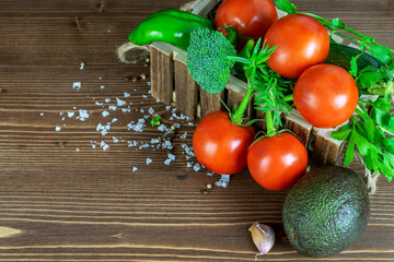 Assortment of fresh raw vegetables in the wooden box on the home kitchen table. Healthy diet food concept.