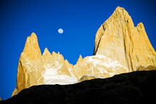 The Full Moon Sets Between Fitz Roy And Poincenot At Sunrise, Patagonia, Argentina.