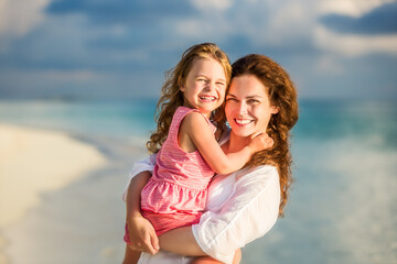 Wall Mural - Portrait of happy mother and little daughter on sunny beach on Maldives at summer vacation