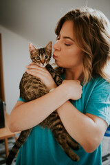 Poster - Vertical shot of a young caucasian female kissing with her cute little kitten