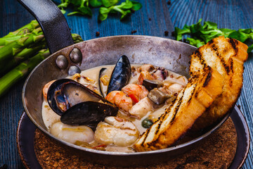 Mixed seafood saute served with toasted bread in a pan