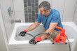 © spatesphoto - Plumber unclogging a bathtub drain
